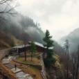 Editorial photograph of a contemporary low-rise timber and stone structure threading through a misty mountain valley.