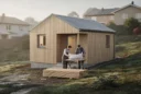 Editorial photograph of a modest, approximately 42-square-metre timber house with a simple pitched roof on.