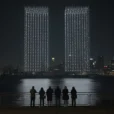 Editorial photographic interpretation of a September memorial drone display over New York Harbor at night, viewed.