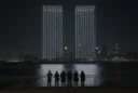 Editorial photographic interpretation of a September memorial drone display over New York Harbor at night, viewed.
