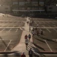Editorial photograph of stadium-bound pedestrians crossing a broad asphalt parking area in Las Vegas, a dark.