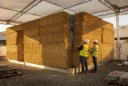 Editorial photograph concept of a compressed-straw building-system mock-up at a New York construction research site, without.