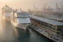 Editorial photograph of PortMiami from an elevated waterfront viewpoint, a slim, elongated contemporary cruise terminal running.