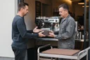 Editorial photograph of a staged café materials collection in Riga, Latvia: a barista hands a closed.