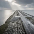 Editorial photograph from an elevated viewpoint on a Dutch coastal dam between the Wadden Sea.
