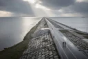 Editorial photograph from an elevated viewpoint on a Dutch coastal dam between the Wadden Sea.