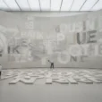 Editorial photograph inside a Paris contemporary art museum, a monumental curved concrete exhibition wall and floor.