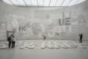 Editorial photograph inside a Paris contemporary art museum, a monumental curved concrete exhibition wall and floor.