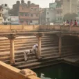 Editorial photograph of a historic sandstone stepwell in Rajasthan, India, viewed diagonally from an upper landing.