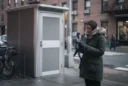 Editorial photograph of a freestanding modular public toilet on a New York City sidewalk, an adult.
