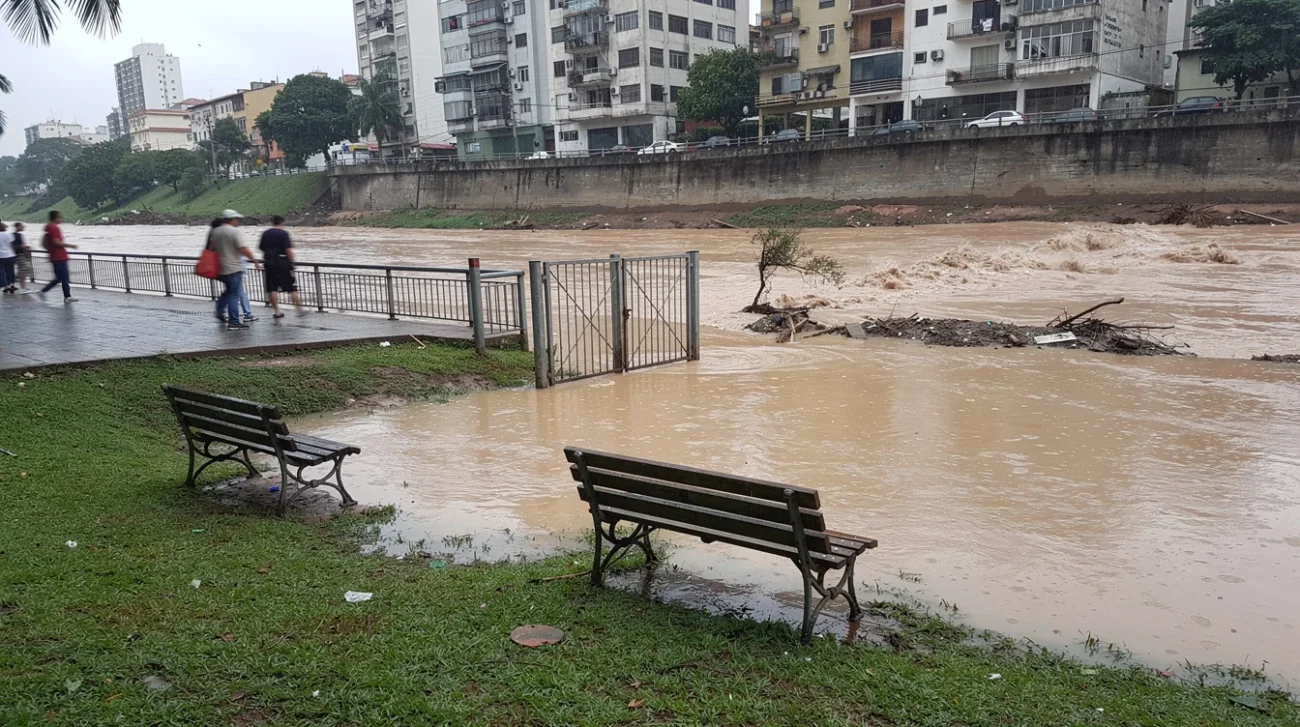 Editorial photograph of a riverside public park in a Brazilian city after heavy rain, muddy floodwater.