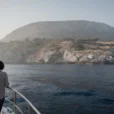 Editorial photograph from a small passenger boat approaching Sazan island, Albania, with its rugged coastline.