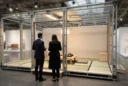 Editorial photograph interpreting the collectible-architecture debate at Design Miami.Paris: a modest demountable house displayed inside.