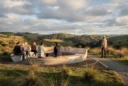 Editorial photograph of a sculptural outdoor gathering place in a New Zealand landscape, with several adults.