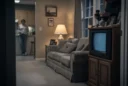 Editorial photograph of a staged early-2000s American suburban living room, beige carpet, patterned sofa, oak television.