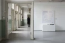 Editorial photograph exploring psychiatric heritage in Denmark: a visitor pauses at the doorway between a retained.