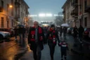 Editorial photograph in Milan’s San Siro district on an autumn football evening: supporters in red-and-black scarves.